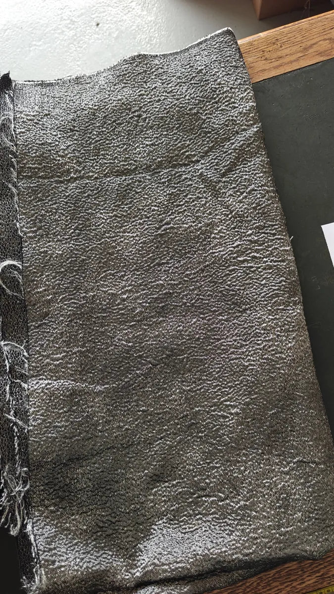 Coupon de tissu noir et argent effet lamé étalé à plat
